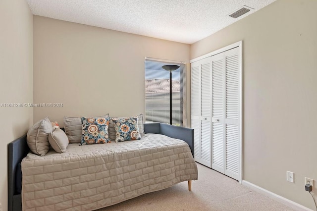 carpeted bedroom featuring a textured ceiling and a closet