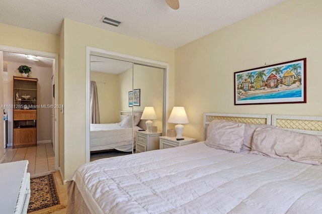 tiled bedroom with ceiling fan, a textured ceiling, and a closet