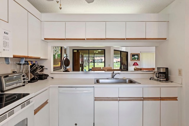 kitchen with white appliances, white cabinetry, and sink