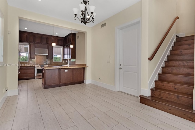 kitchen with pendant lighting, kitchen peninsula, stainless steel range, a notable chandelier, and dark brown cabinets