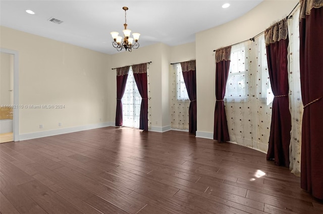 empty room featuring a chandelier and dark hardwood / wood-style floors