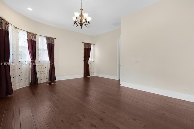 empty room featuring a chandelier and dark hardwood / wood-style floors