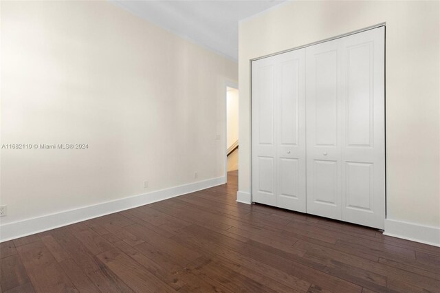 unfurnished bedroom featuring dark hardwood / wood-style flooring and a closet