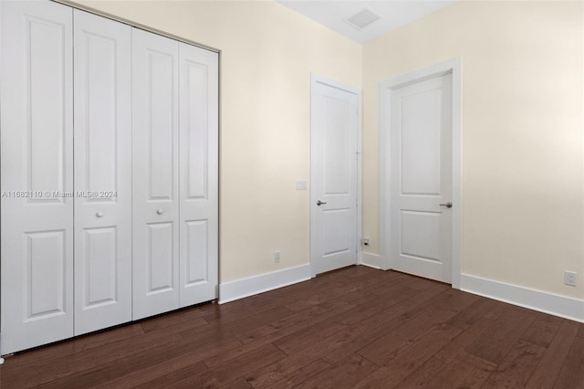 unfurnished bedroom featuring dark hardwood / wood-style flooring and a closet