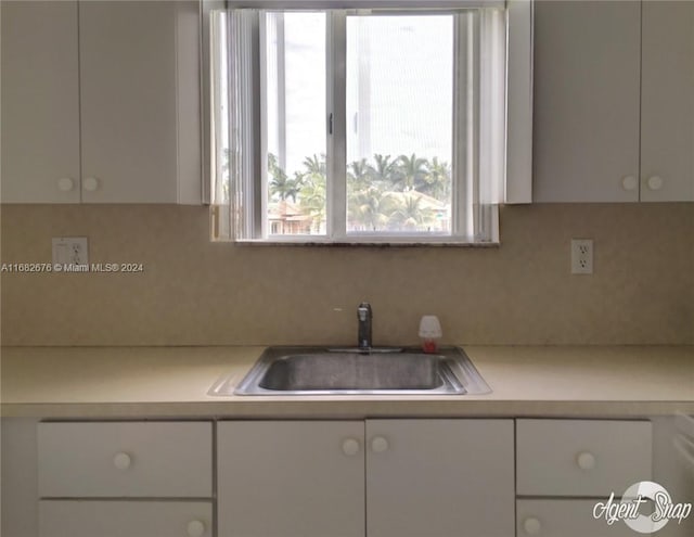 kitchen featuring tasteful backsplash, sink, and white cabinets