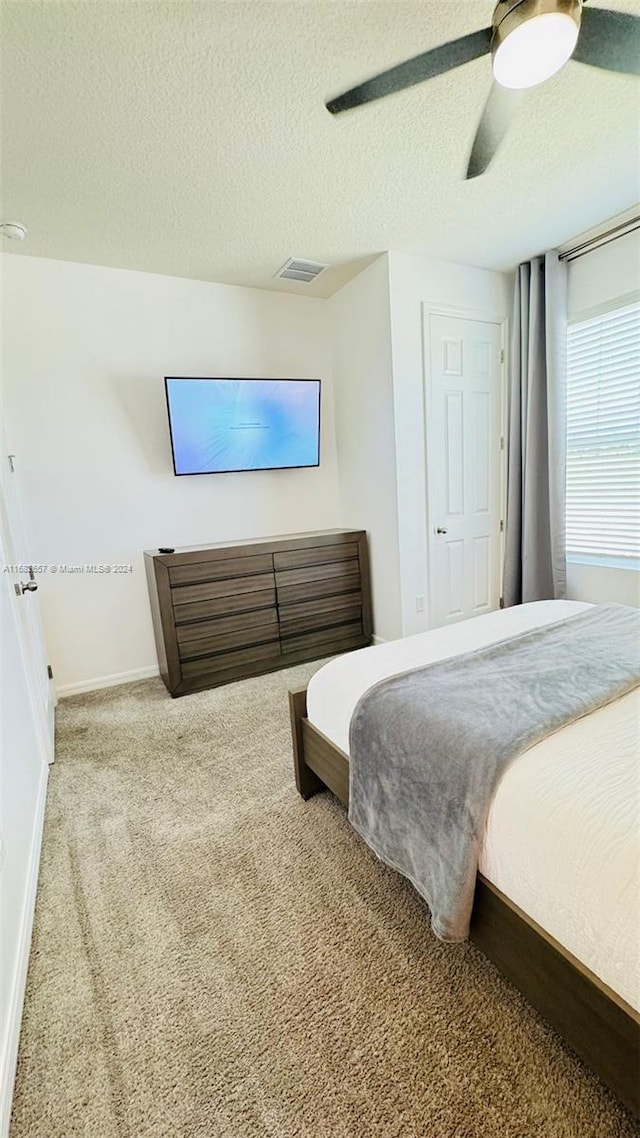 bedroom featuring a textured ceiling, carpet flooring, and ceiling fan