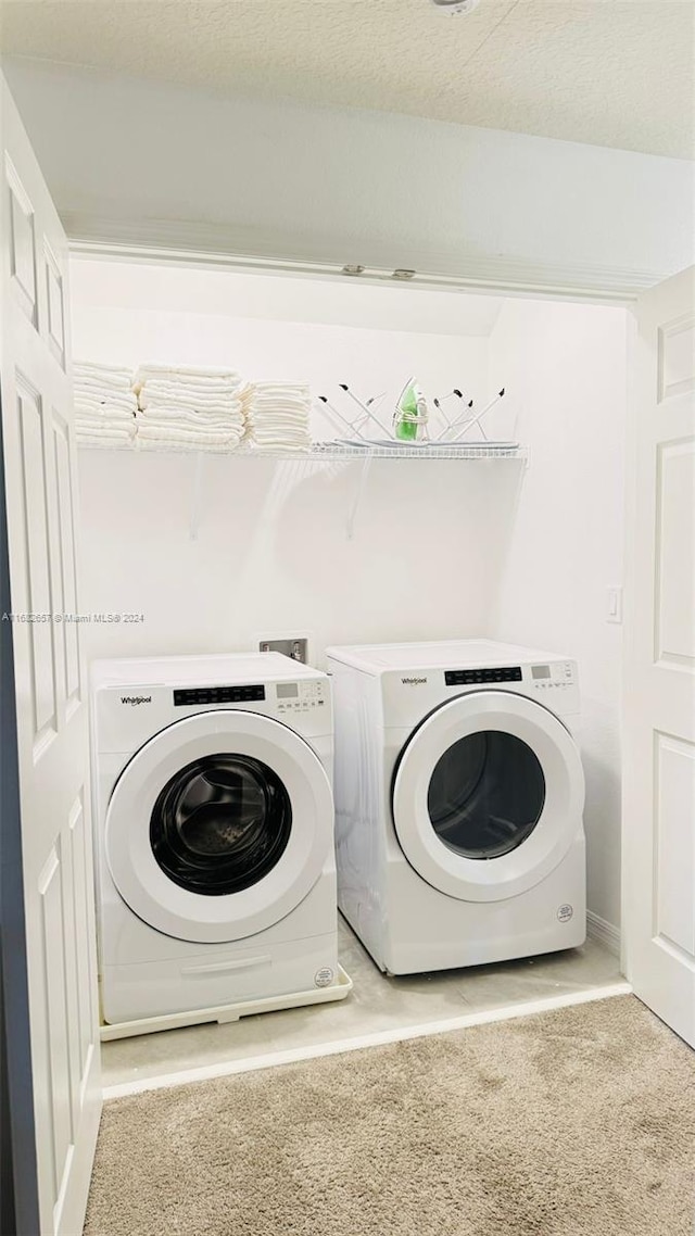 washroom with light carpet, washing machine and dryer, and a textured ceiling