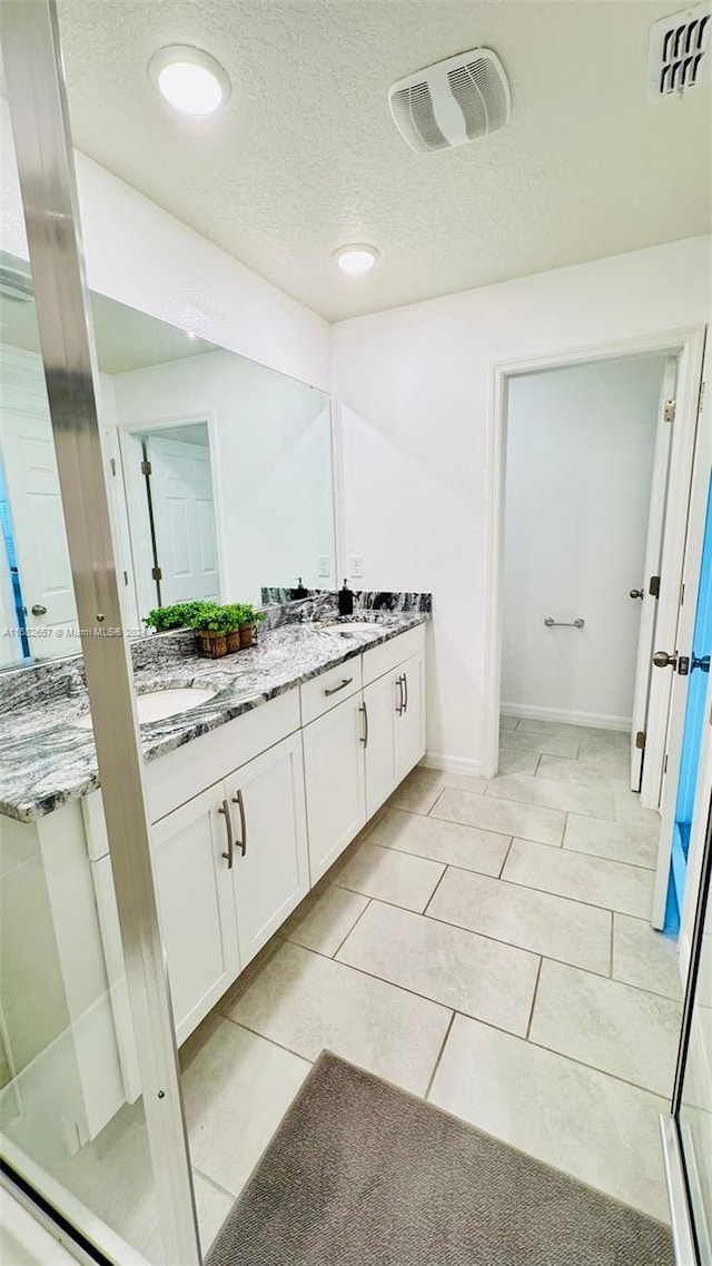 bathroom with vanity, a textured ceiling, and tile patterned flooring