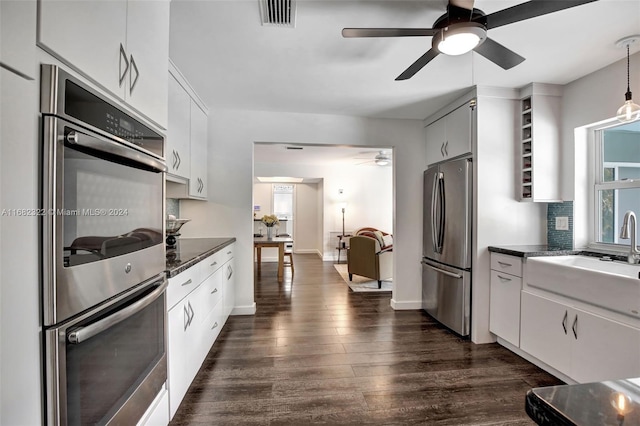 kitchen with sink, white cabinetry, stainless steel appliances, decorative light fixtures, and dark hardwood / wood-style floors