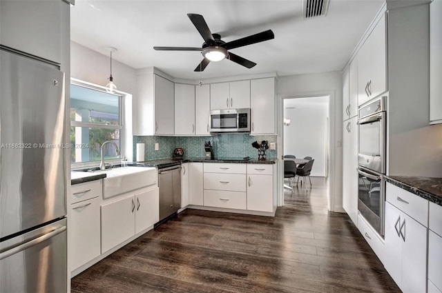 kitchen with appliances with stainless steel finishes, dark hardwood / wood-style flooring, and white cabinets