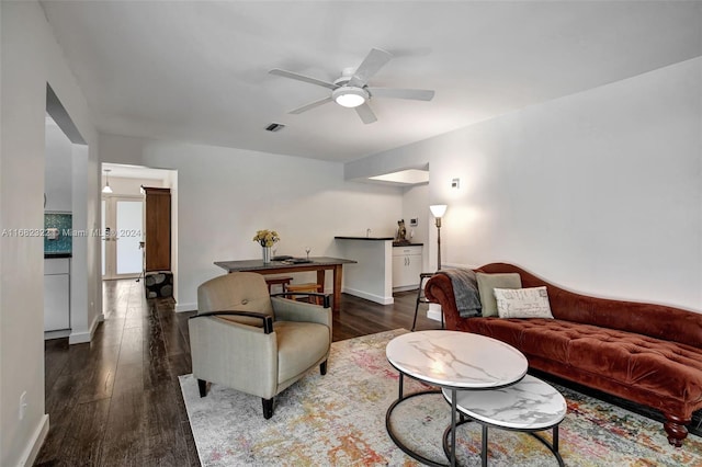 living room featuring dark wood-type flooring and ceiling fan