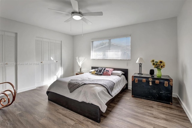 bedroom featuring multiple closets, hardwood / wood-style flooring, and ceiling fan