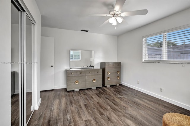 unfurnished bedroom with a closet, dark wood-type flooring, and ceiling fan