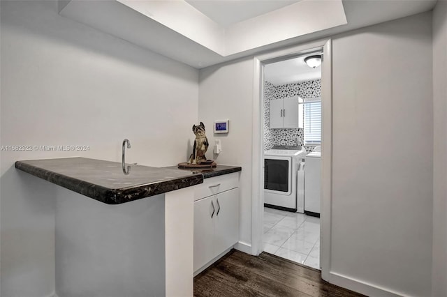 kitchen featuring kitchen peninsula, backsplash, white cabinetry, dark wood-type flooring, and washer and clothes dryer