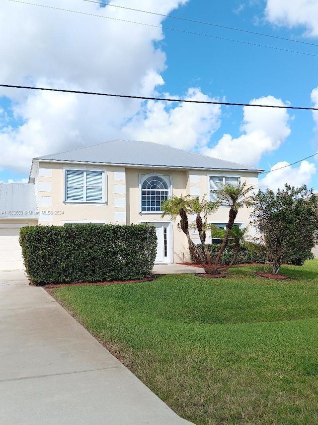 view of front facade with a front lawn, driveway, and stucco siding