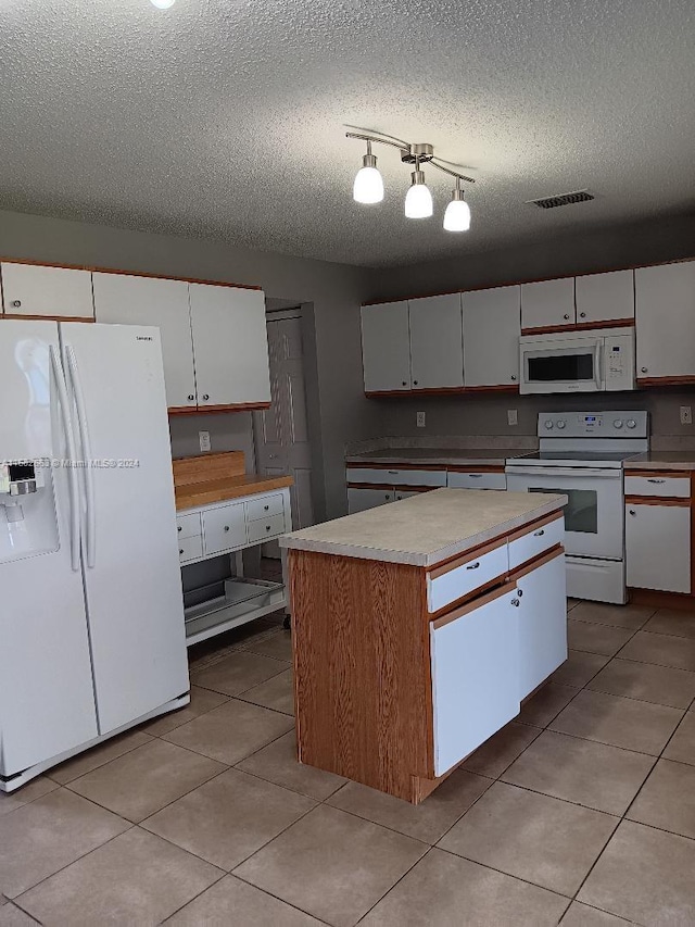 kitchen with white appliances, light tile patterned flooring, a textured ceiling, a center island, and white cabinets