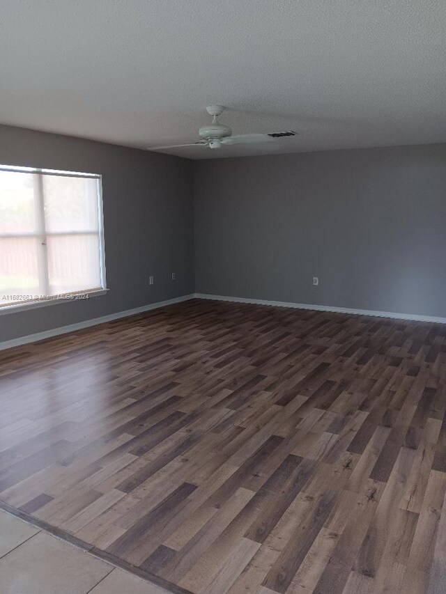 empty room with dark hardwood / wood-style floors, a textured ceiling, and ceiling fan