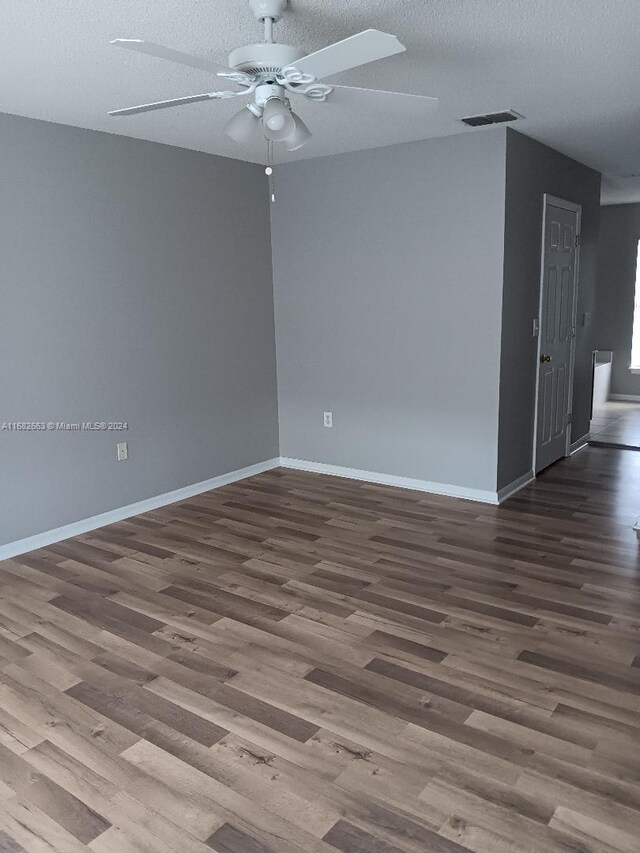 spare room with baseboards, visible vents, wood finished floors, and ceiling fan
