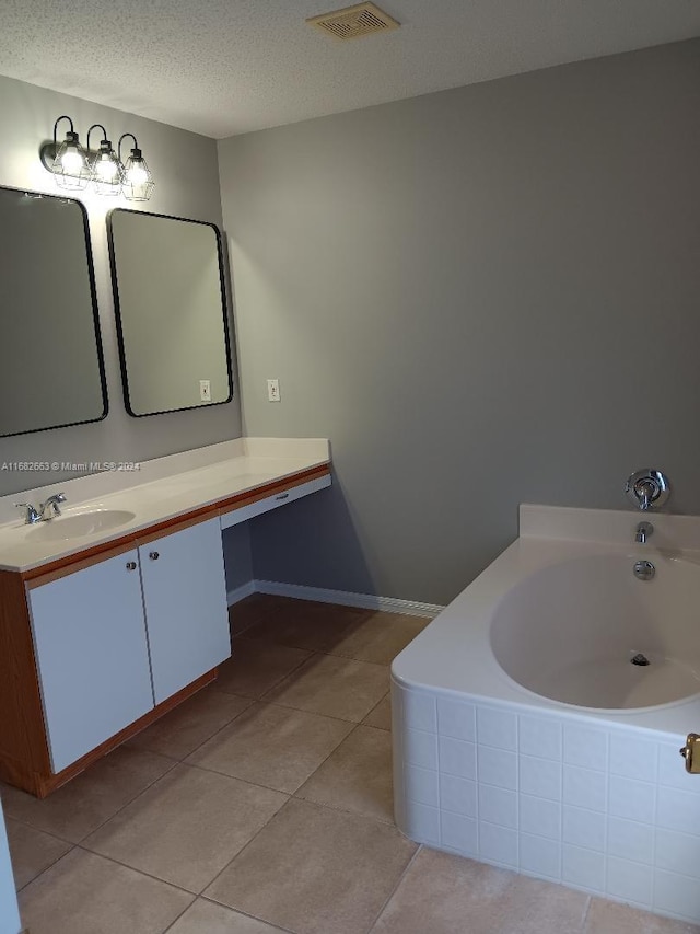 bathroom featuring vanity, a textured ceiling, tiled tub, and tile patterned floors