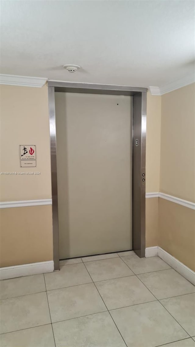 hallway featuring ornamental molding, elevator, and light tile patterned floors