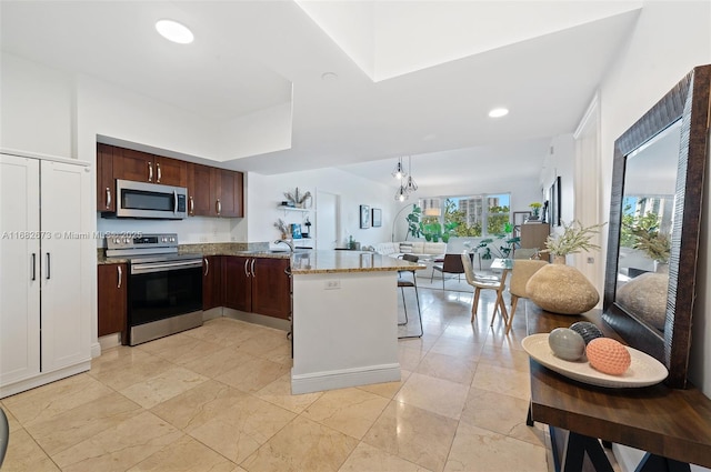 kitchen with light stone counters, stainless steel appliances, and kitchen peninsula