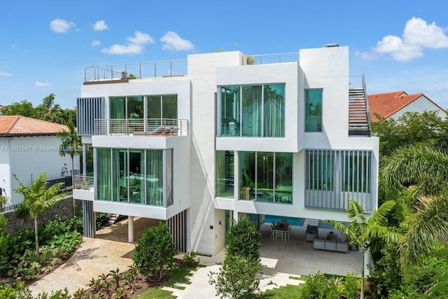 back of house with a patio area, a balcony, and an outdoor living space