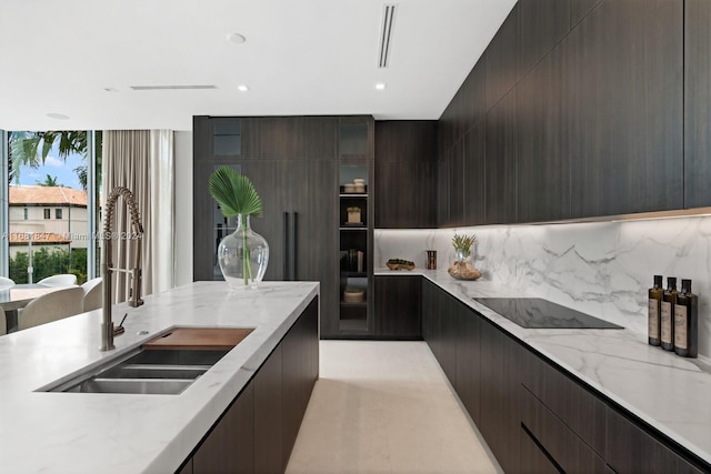 kitchen with black electric stovetop, dark brown cabinetry, sink, and backsplash