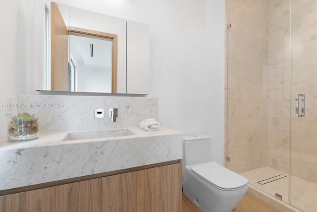 bathroom featuring a shower with door, vanity, backsplash, and toilet