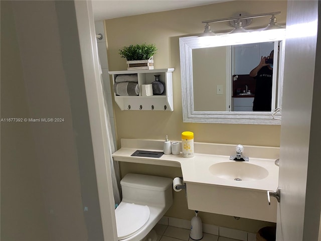 bathroom with toilet, vanity, and tile patterned flooring