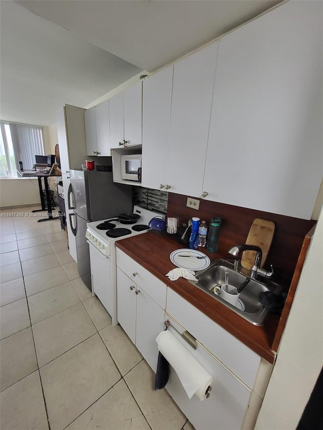 kitchen featuring light tile patterned flooring, white cabinets, sink, and white appliances