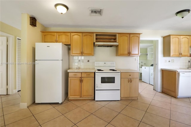 kitchen with light brown cabinets, extractor fan, backsplash, washer and dryer, and white appliances