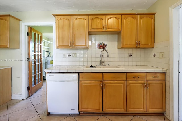 kitchen featuring dishwasher, tile counters, backsplash, sink, and light tile patterned floors