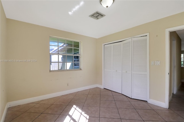 unfurnished bedroom with a closet and light tile patterned floors