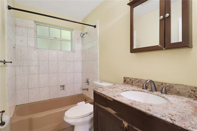 full bathroom featuring tiled shower / bath, vanity, and toilet