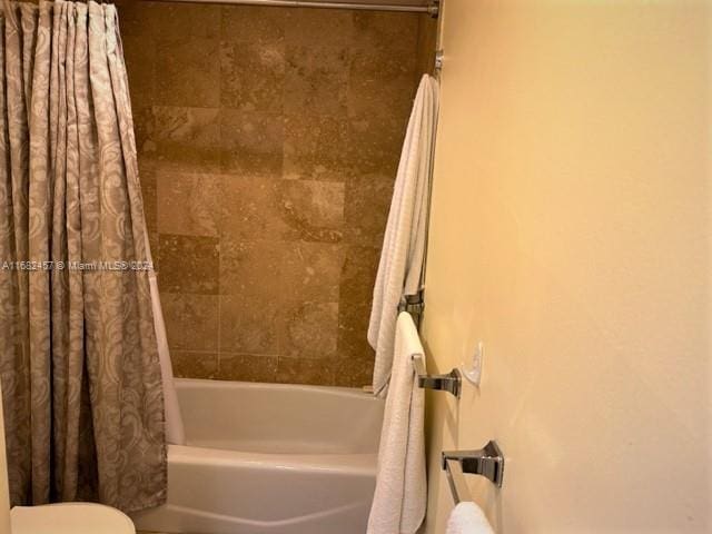 bathroom featuring toilet and shower / tub combo with curtain