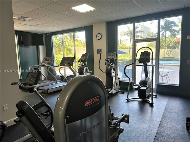 workout area with visible vents, a drop ceiling, and plenty of natural light