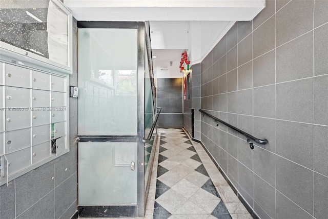 bathroom with tile walls, a shower, and a mail area