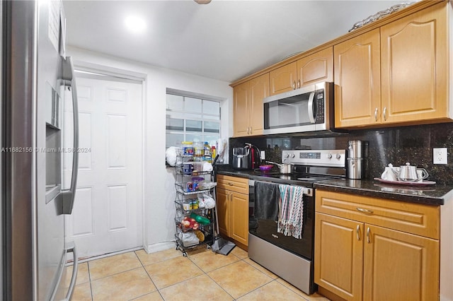 kitchen featuring dark stone countertops, stainless steel appliances, light tile patterned floors, and tasteful backsplash