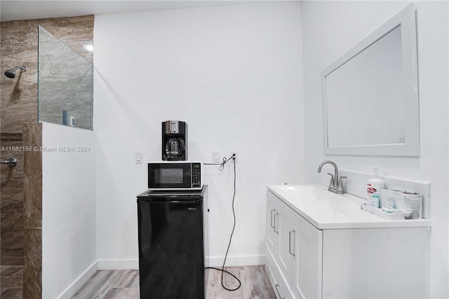 bathroom featuring vanity, tiled shower, and hardwood / wood-style flooring