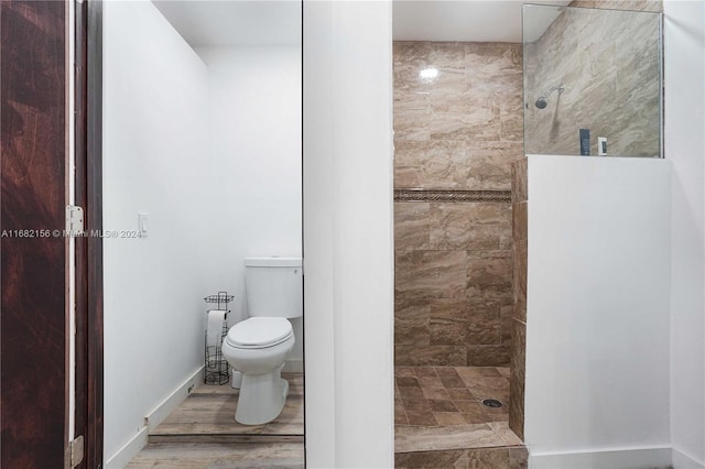 bathroom featuring a tile shower, toilet, and hardwood / wood-style floors