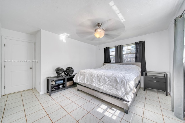 tiled bedroom with ceiling fan and a textured ceiling