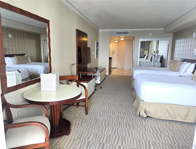 bedroom featuring ornamental molding, light carpet, and a textured ceiling