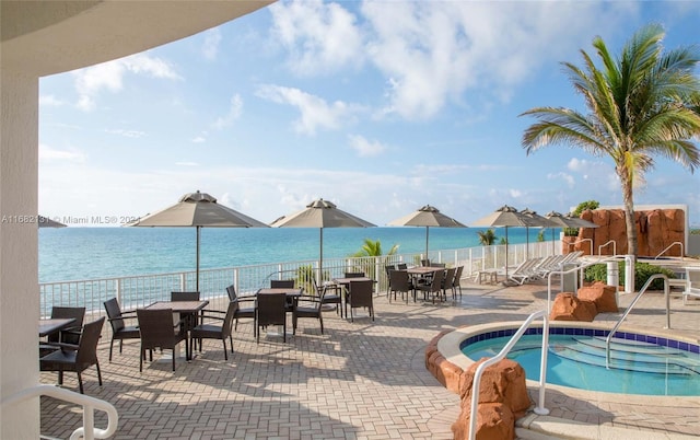 view of pool with a patio area, a hot tub, and a water view