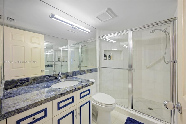 bathroom featuring vanity, tile patterned flooring, toilet, and walk in shower