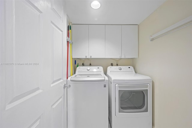 washroom featuring cabinets and washer and clothes dryer