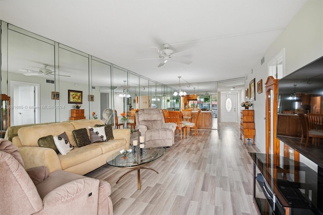 living room with light hardwood / wood-style flooring and ceiling fan with notable chandelier