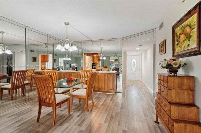 dining room with light hardwood / wood-style flooring and an inviting chandelier