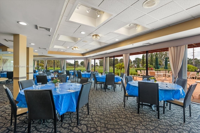 carpeted dining area with a paneled ceiling