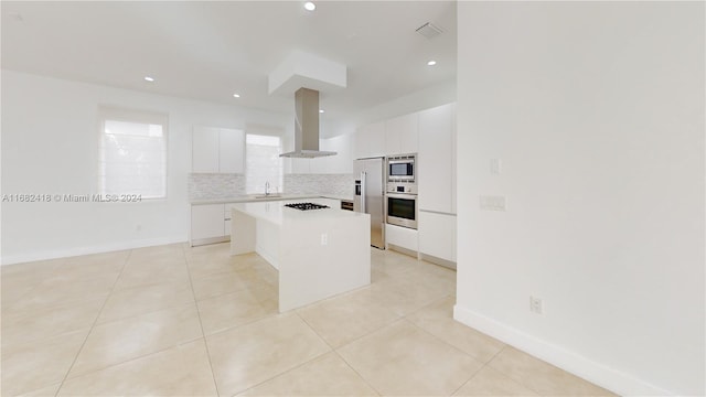 kitchen with appliances with stainless steel finishes, a kitchen island, a breakfast bar area, white cabinets, and exhaust hood