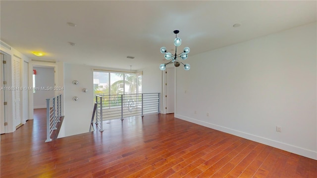 spare room featuring a chandelier and wood-type flooring